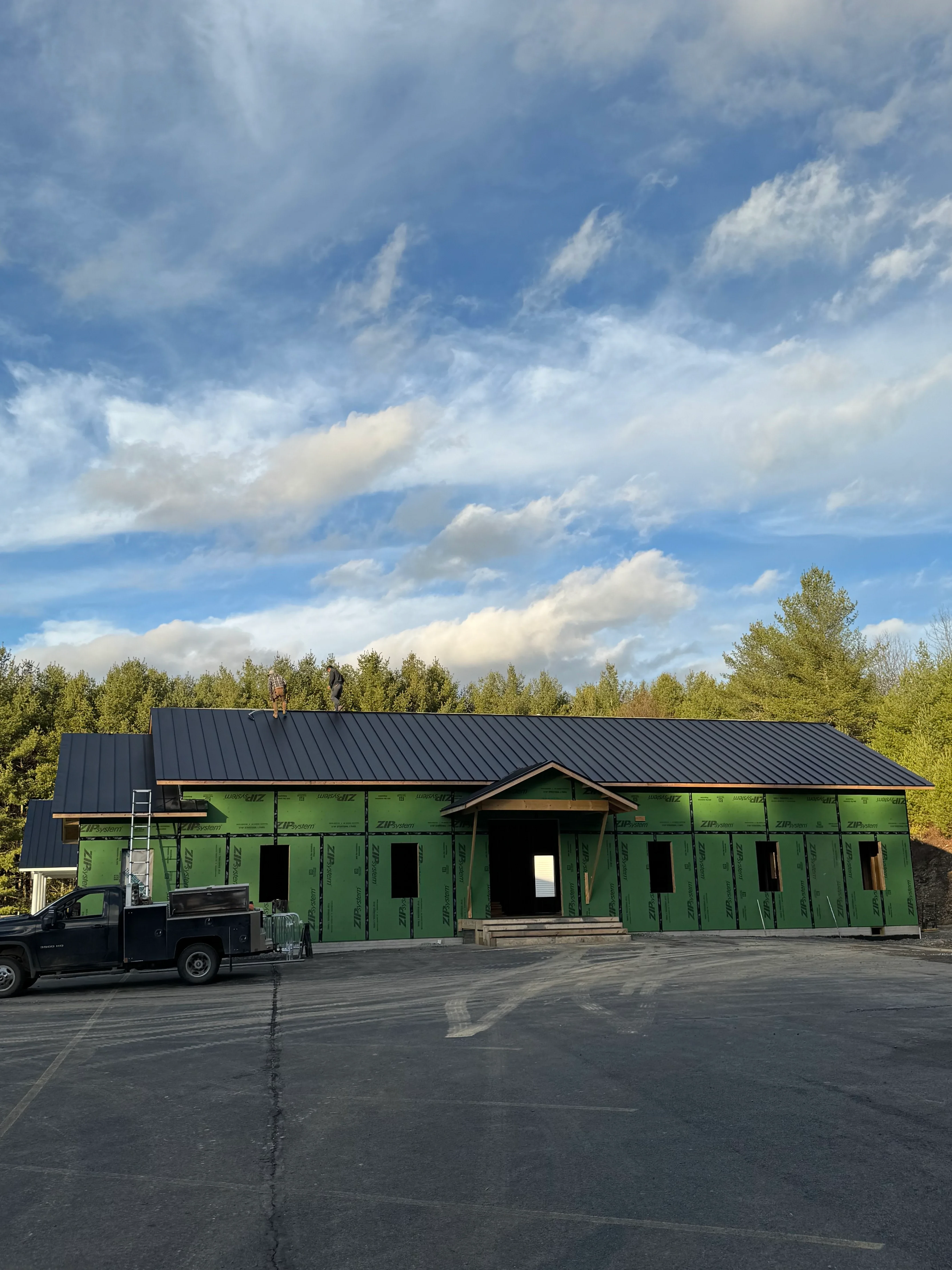 Standing seam metal roof installation on agricultural building with gray metal panels and flashing details