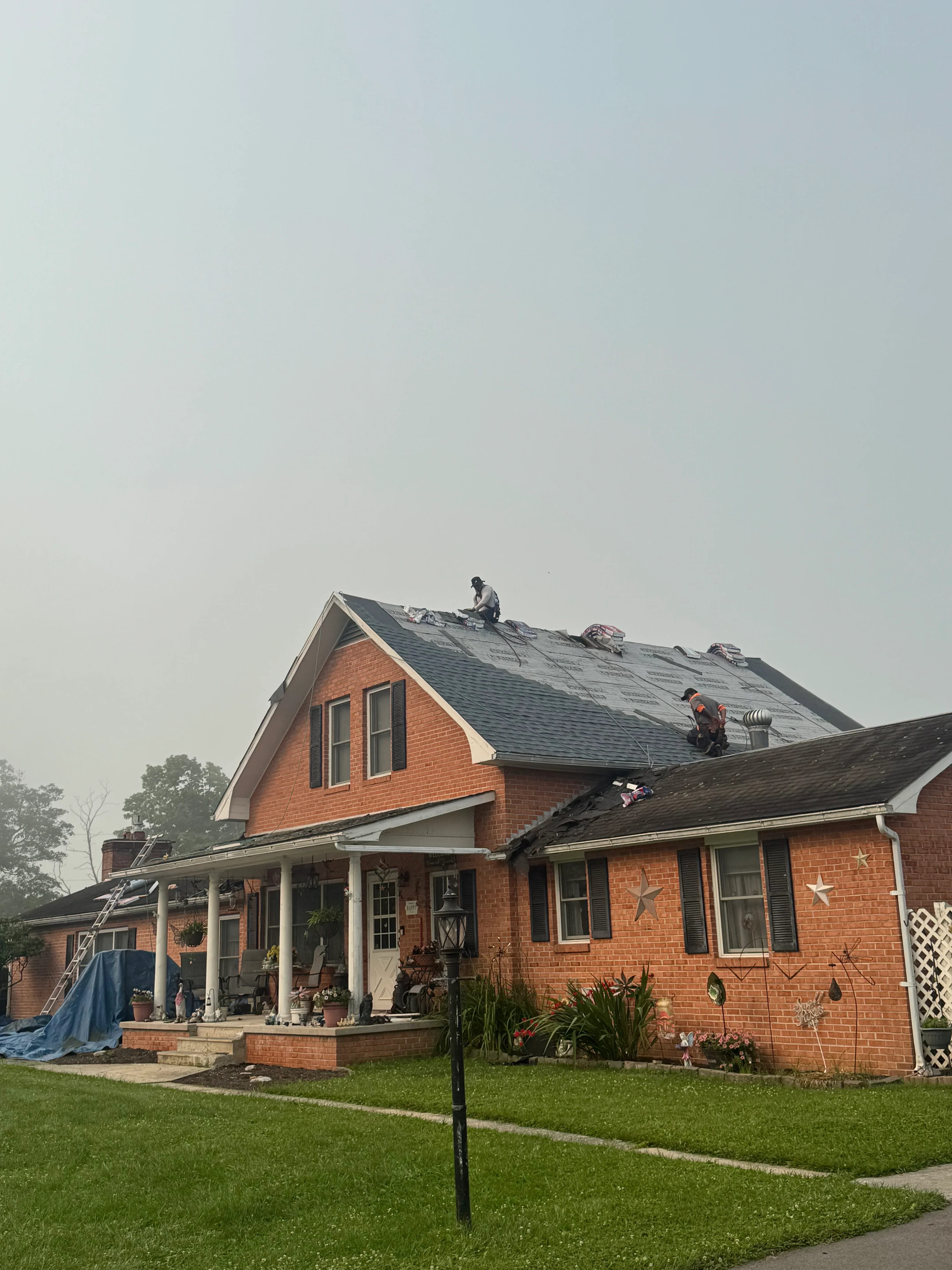 New charcoal gray asphalt shingle roof installed on two-story brick home with pitched design