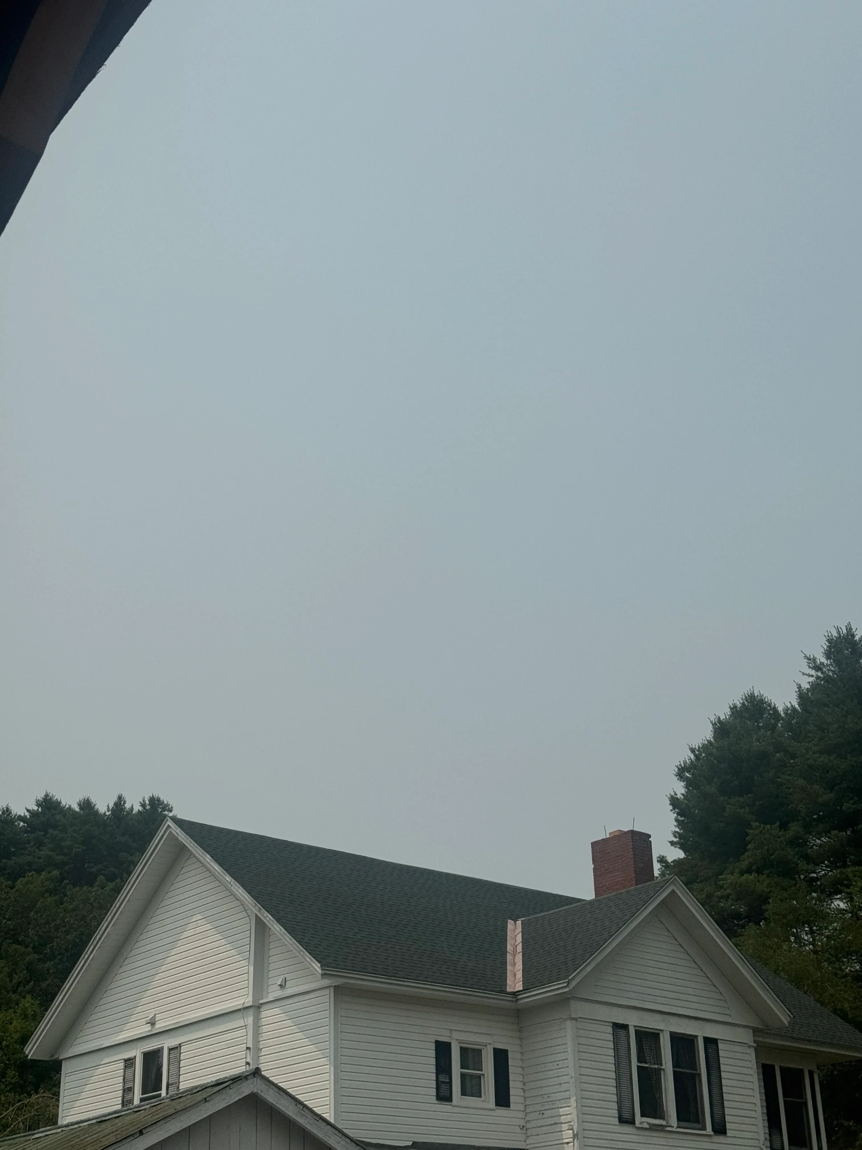 Metal standing seam roof installation with gray panels and chimney flashing on residential home